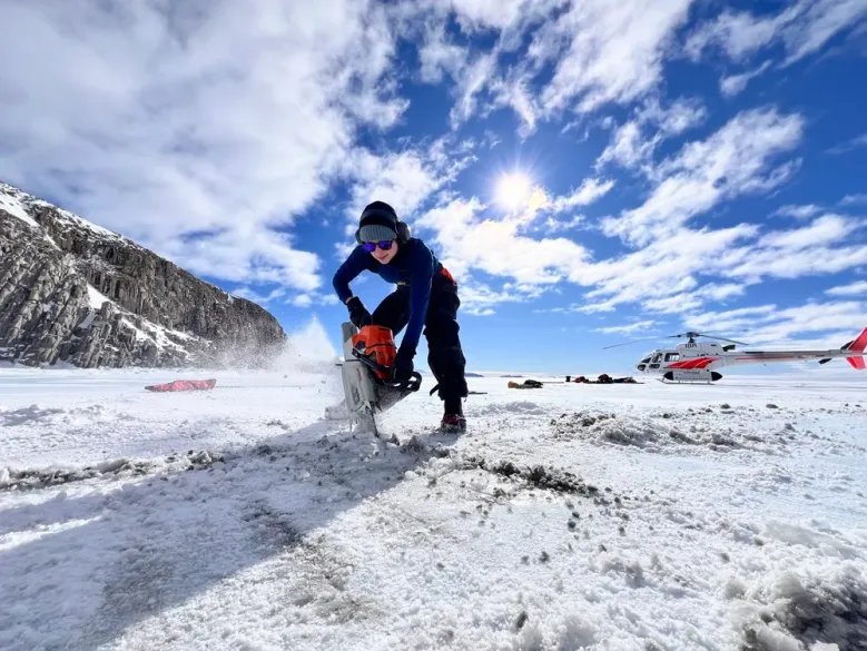 A photograph of Sarah Seabrook cutting holes in the ice with a chainsaw to access the ocean beneath.